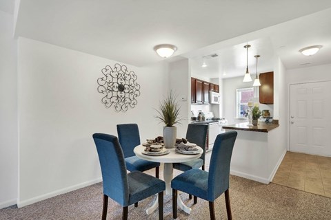 A dining room with a table set for two and a decorative wall hanging.
