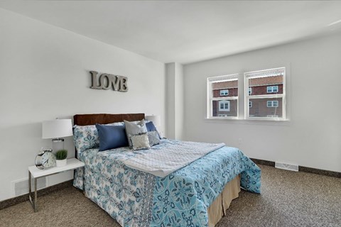 A bedroom with a bed, nightstand, and a wall decoration that says "LOVE".
