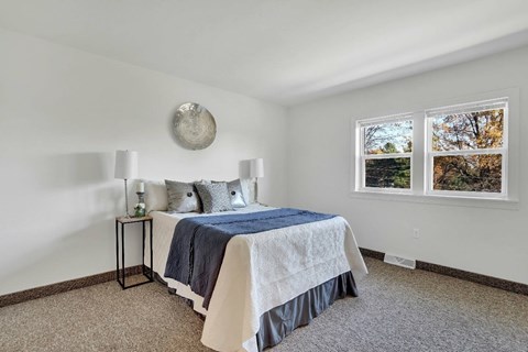 A bedroom with a bed, nightstand, and window.