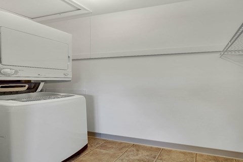 A white dishwasher is in a kitchen with white walls.
