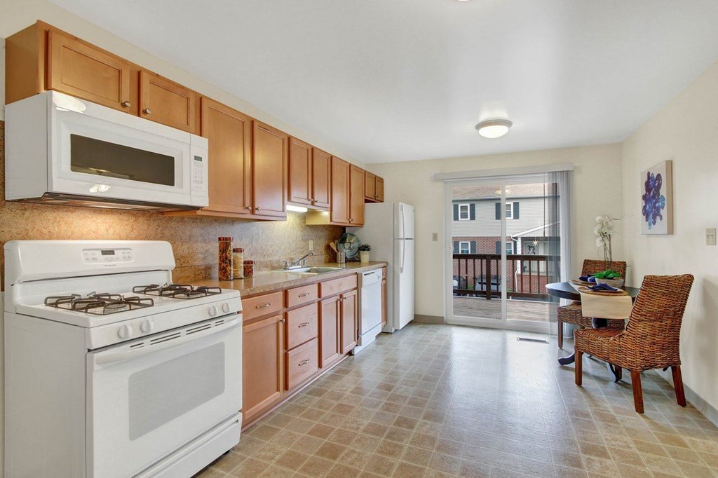 A kitchen with white and brown cabinets and a white stove.