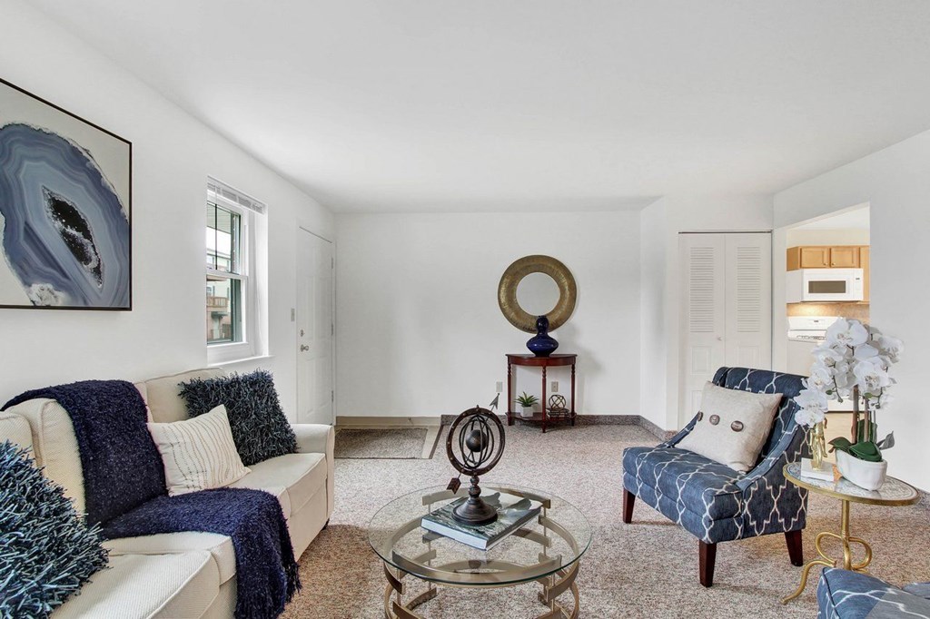 A living room with a white couch, a blue chair, and a glass coffee table.