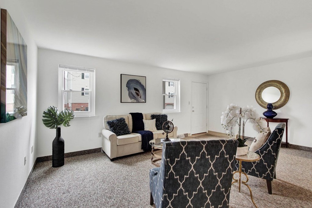 A living room with a grey carpet and a white couch.