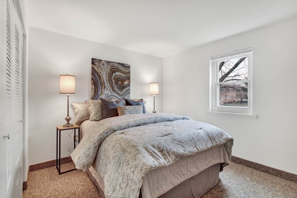 A bedroom with a large bed and two lamps on either side of the bed.