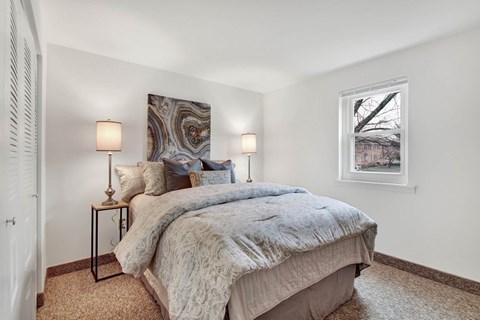 A bedroom with a large bed and two lamps on either side of the bed.