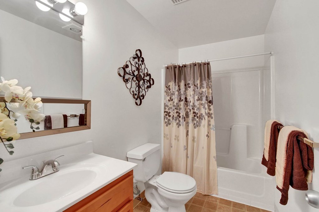A white bathroom with a toilet, sink, and shower.