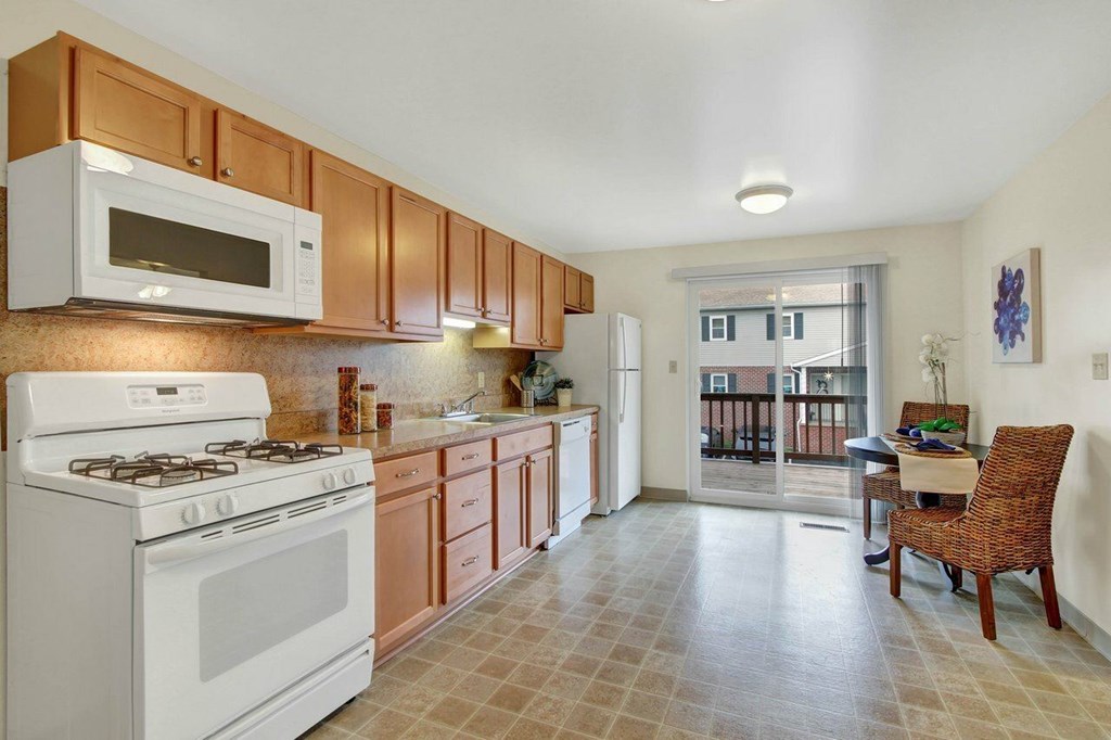 A kitchen with white and brown cabinets and a white stove.