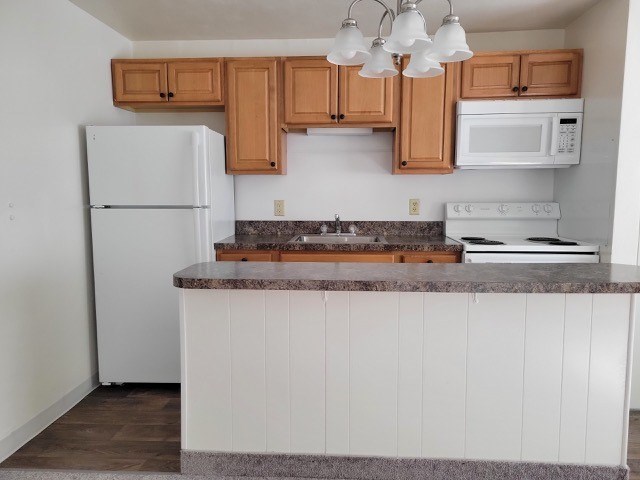 A kitchen with white appliances and wooden cabinets.