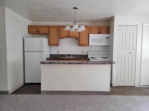 A kitchen with white cabinets and a white fridge.