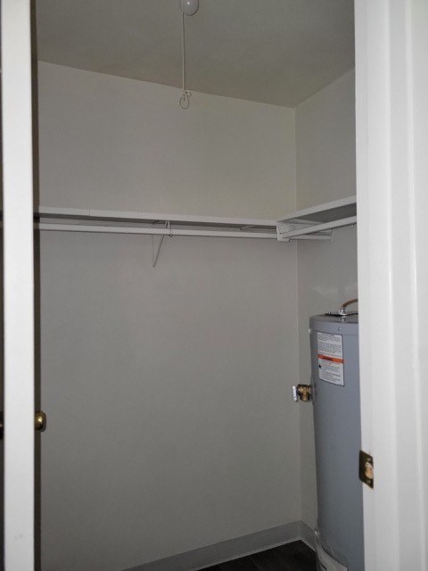 A small room with a grey fridge and a white door.