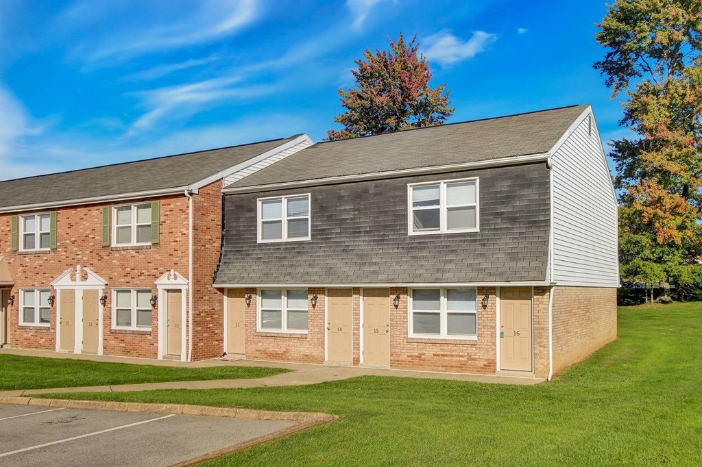 A building with a grey roof and a brick facade with white doors and windows.