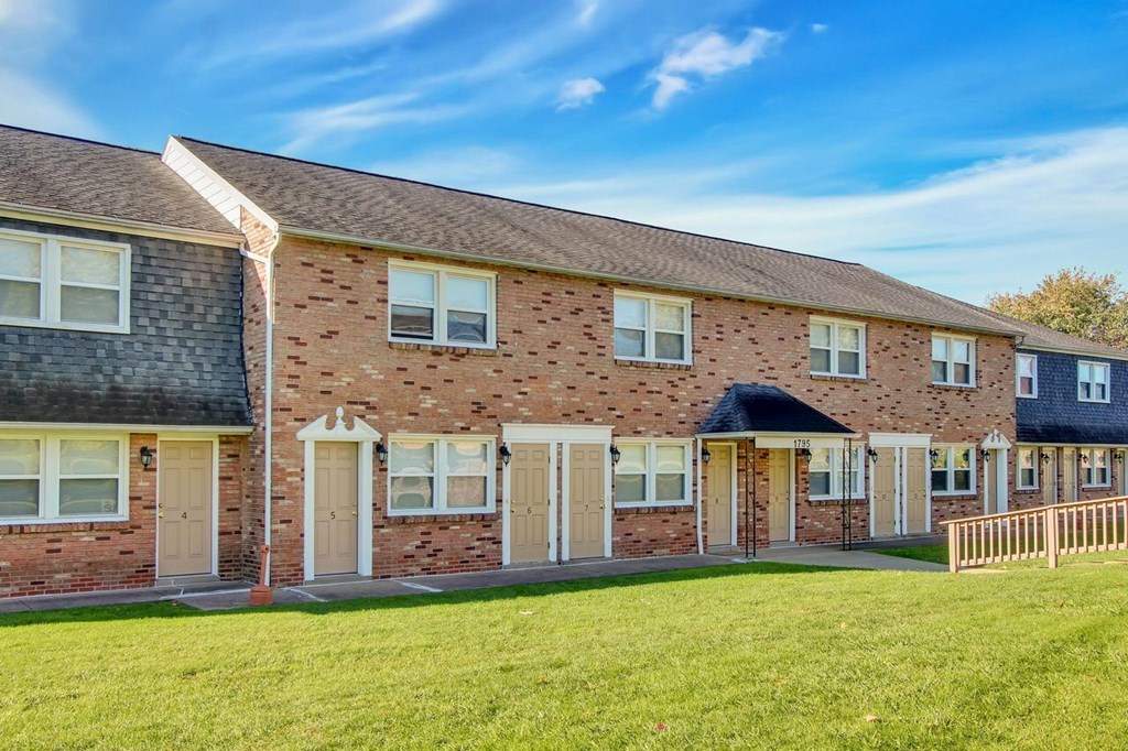 A row of houses with brown brick walls and white windows.