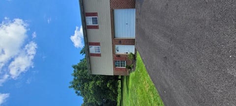 A building with a grey wall and a blue sky with clouds.