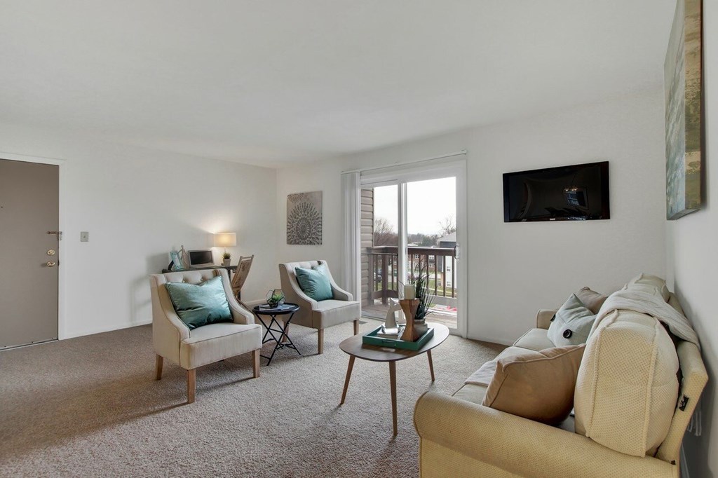 A living room with a couch, chairs, and a television.