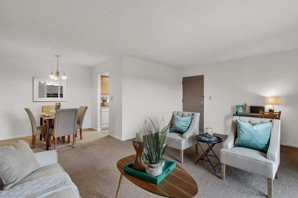 A living room with a grey couch, a wooden coffee table, and a dining table with chairs.
