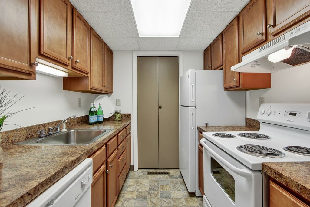 A kitchen with brown cabinets and a white stove top oven.