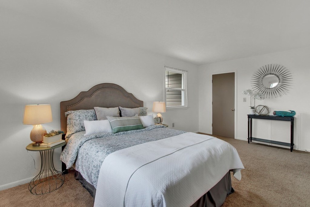 A bedroom with a large bed and a mirror on the wall.