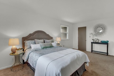 A bedroom with a large bed and a mirror on the wall.