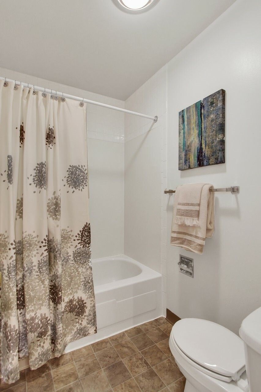 A bathroom with a toilet, a bathtub, and a shower curtain.