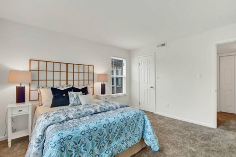 A bedroom with a bed, nightstand, and window.