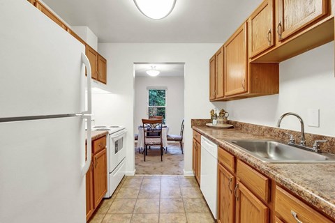 A kitchen with a white refrigerator and wooden cabinets.
