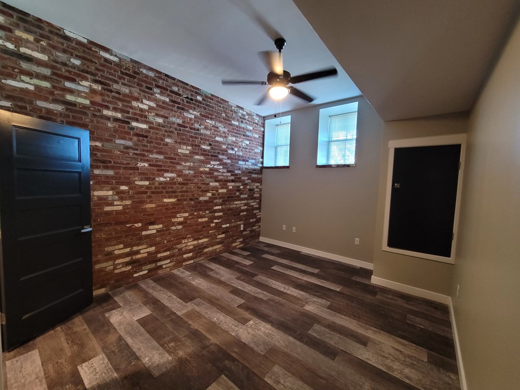 A room with a brick wall and a ceiling fan.