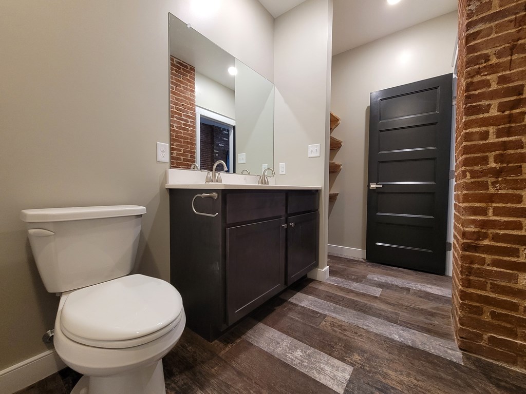 A bathroom with a toilet, sink, and a mirror.