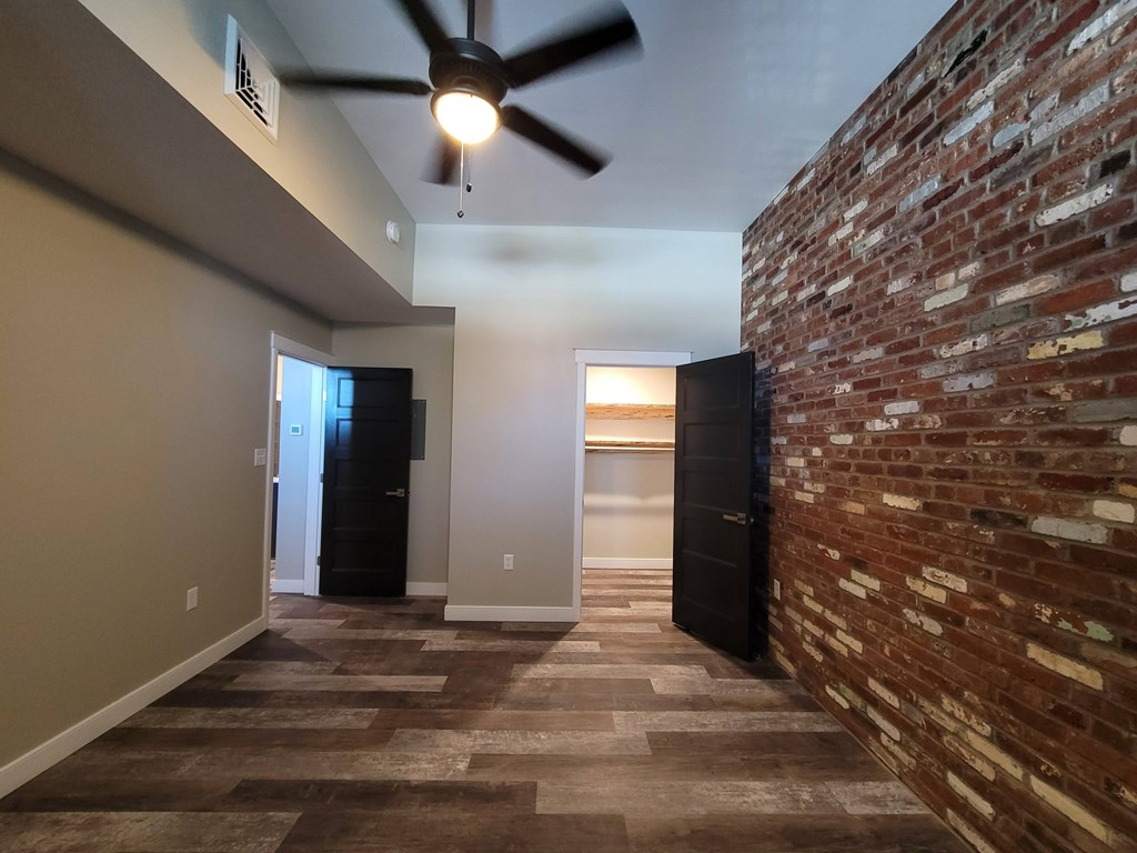 A room with a brick wall and a ceiling fan.