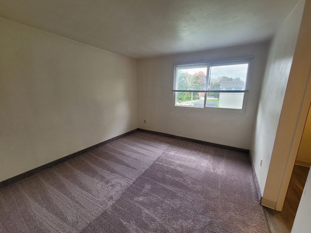 A room with a carpeted floor and a window.