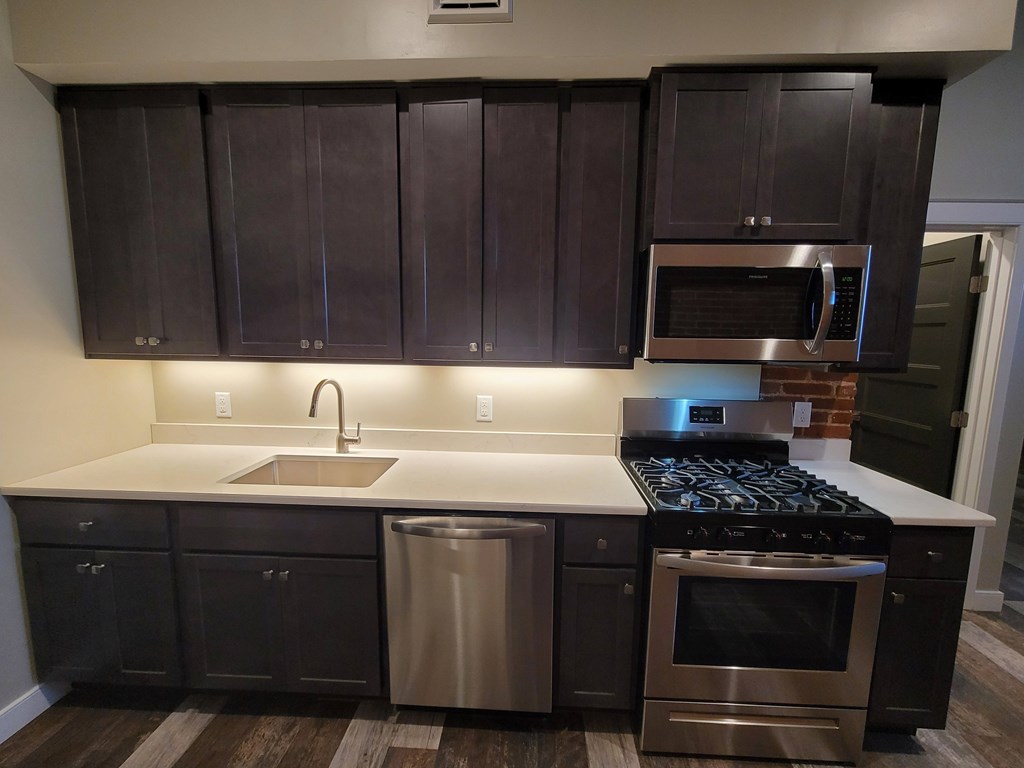 A kitchen with dark brown cabinets and stainless steel appliances.