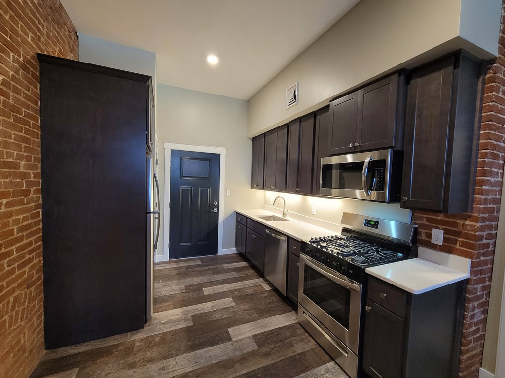 A kitchen with a black fridge and stove top oven.