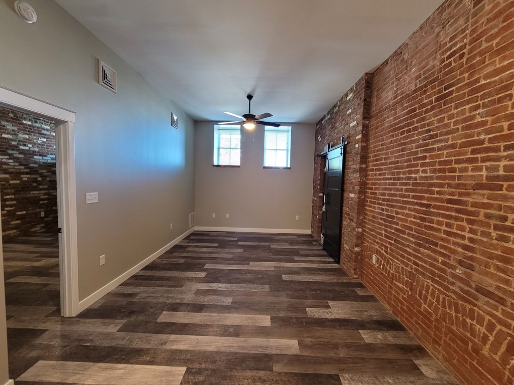 A room with a brick wall and a ceiling fan.