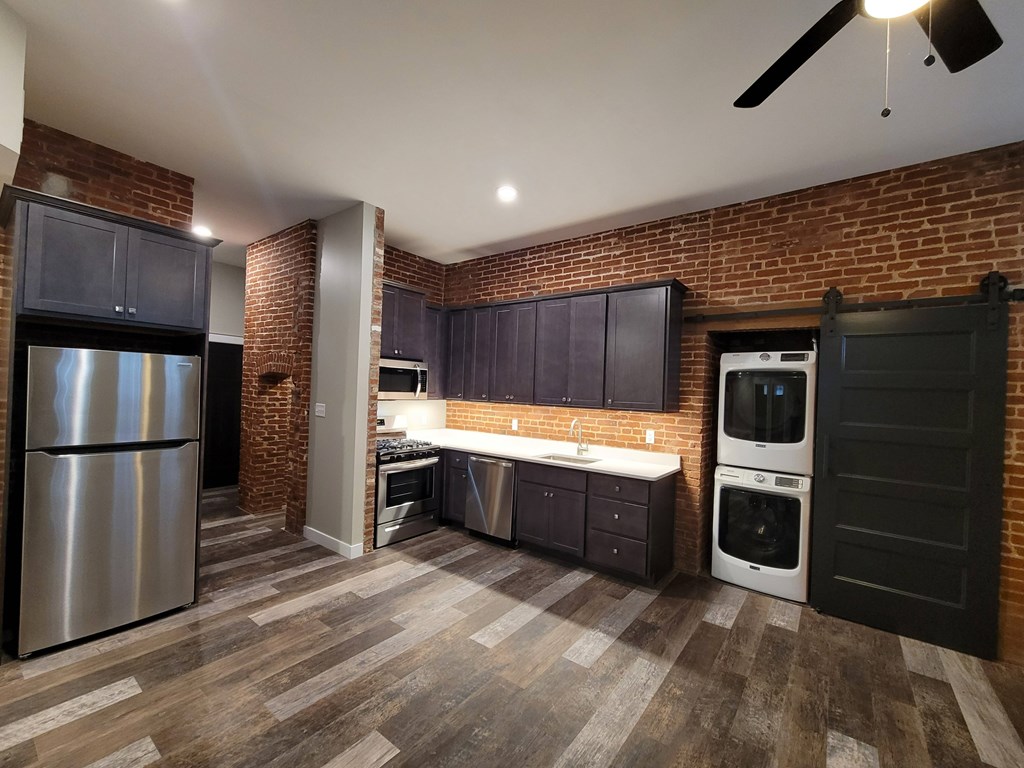 A kitchen with a refrigerator, oven, and sink.