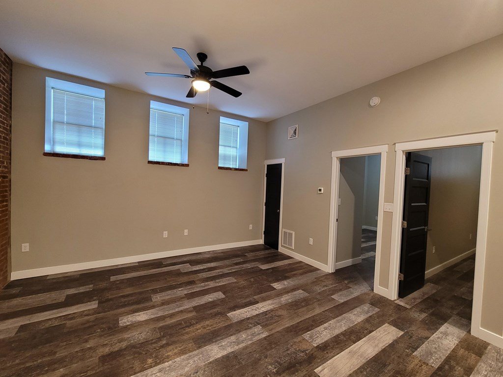 A room with a ceiling fan and wooden flooring.