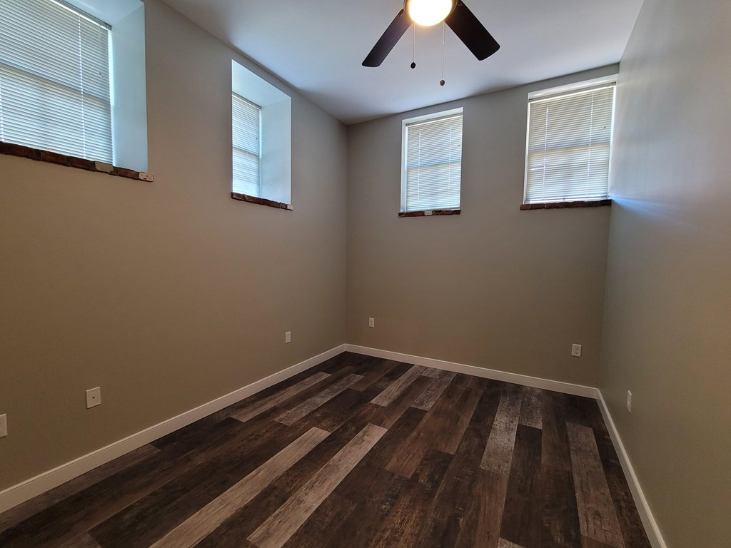A room with wooden flooring and a ceiling fan.