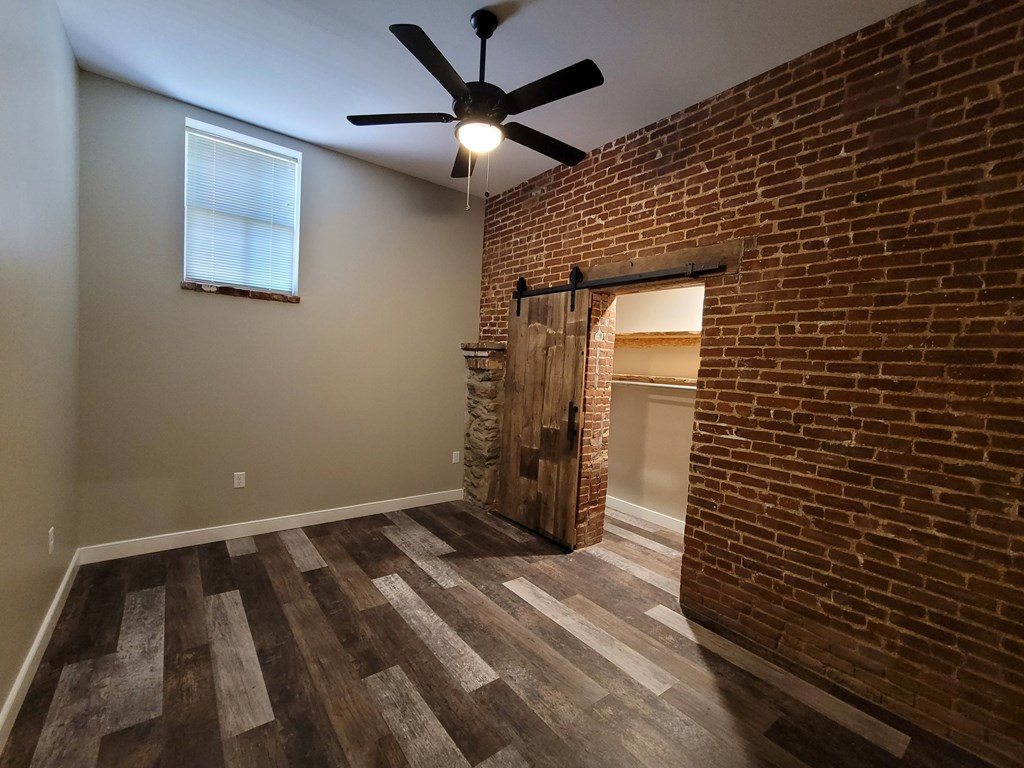 A room with a brick wall and a ceiling fan.