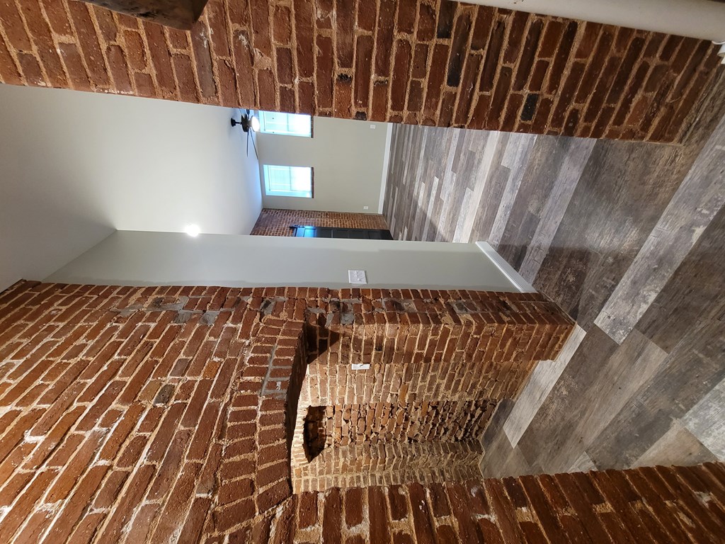 A staircase with a brick patterned wall on the side and a window in the distance.