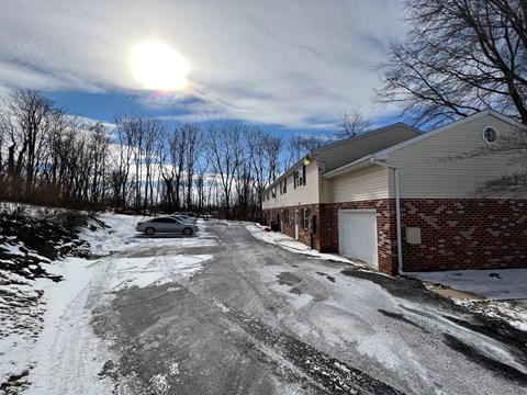 A snowy residential street with a house on the right.