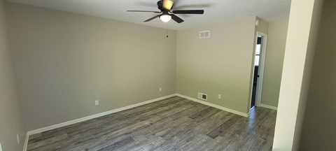 A room with a ceiling fan and wood flooring.