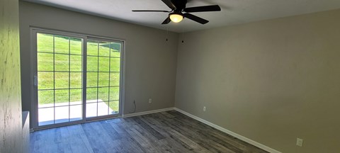 A room with a sliding glass door leading to a green lawn.
