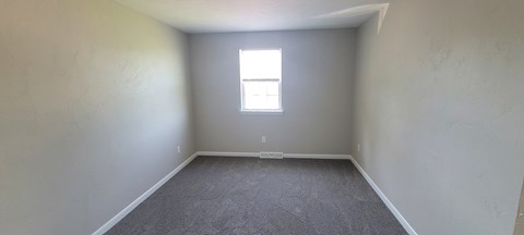 A room with a window and carpeted floor.