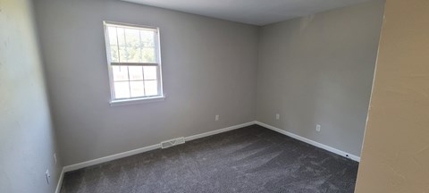 A room with a window and carpeted floor.