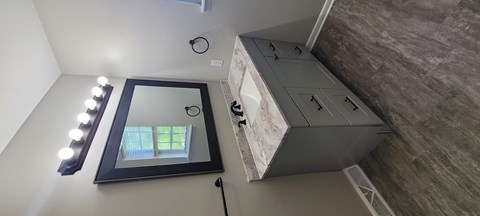 A mirror with lights on the side is on a wall.