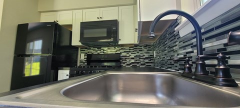 A kitchen with a black fridge and microwave.