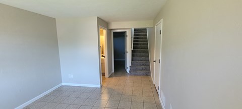 A hallway with a staircase and a door at the end.