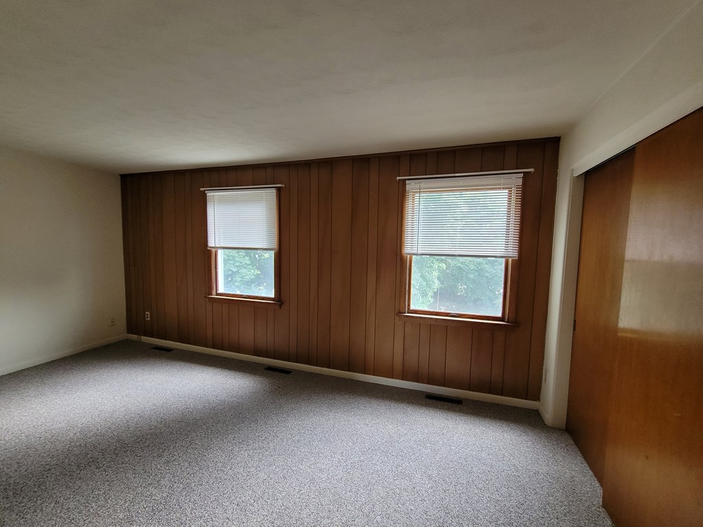 A room with two windows and a carpeted floor.