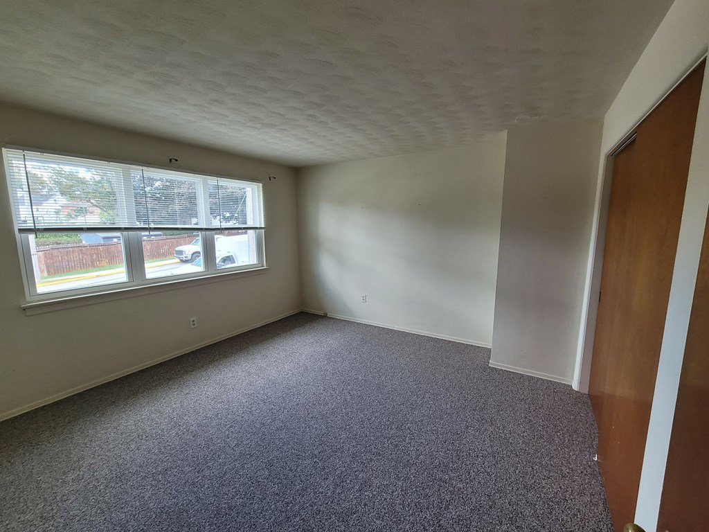 A room with a carpeted floor and a window.