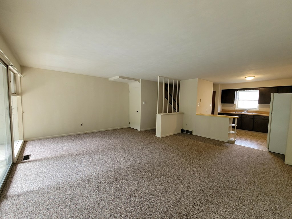 A large, empty room with carpeted flooring and white walls.