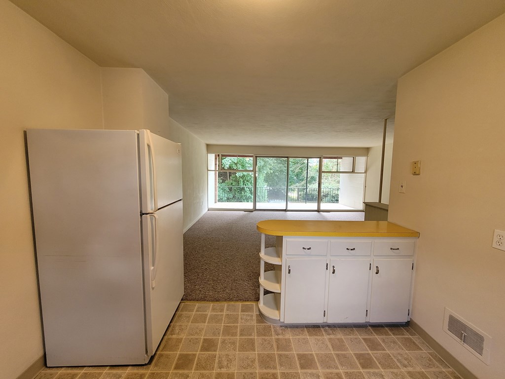 A kitchen with a white refrigerator and white cabinets with a yellow counter top.