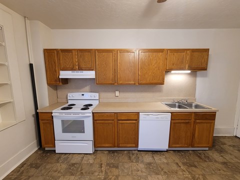 A kitchen with a white stove and white dishwasher.